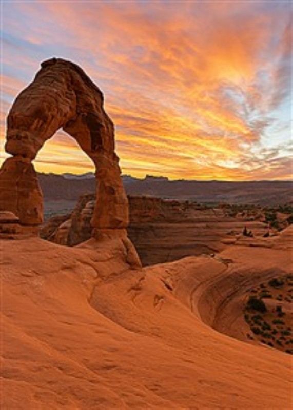 Magisk solnedgang over Delicate Arch - Oplev den magiske skønhed i en solnedgang, der oplyser Delicate Arch i Utah. De farverige himmelstræk og den unikke sandstenslandskab skaber en atmosfære af ro og inspiration.